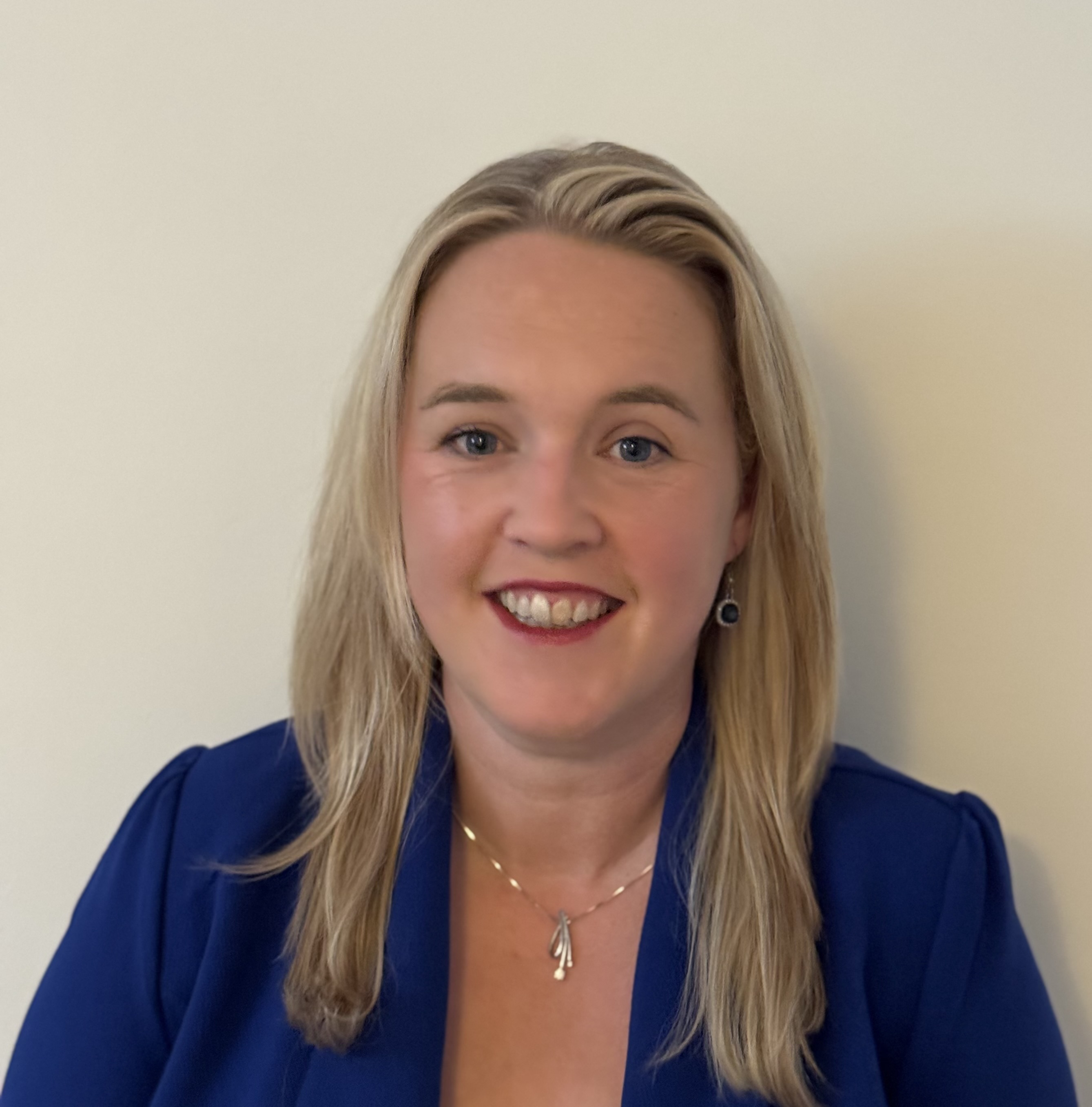Headshot of Eithne. She has long blonde hair and is wearing a blue top